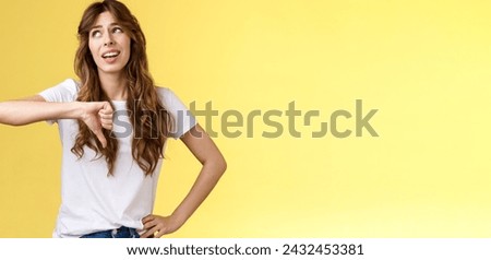 Blah blah boring. Unimpressed apathetic snobbish attractive curly-haired girl look away express scorn disdain show thumb down frowning sharing negative judgement bad opinion yellow background. Royalty-Free Stock Photo #2432453381
