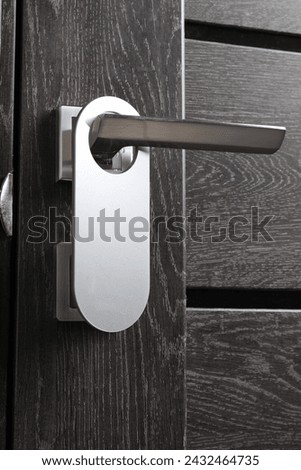 Closed wooden door with blank hanger on metal handle, closeup