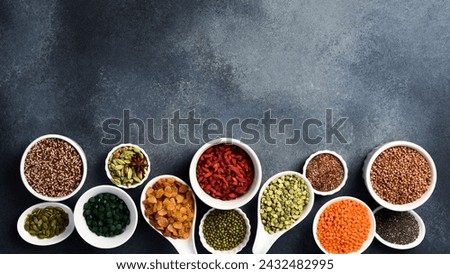 Set of superfoods, cereals, nuts and dried fruits, spirulina and goji in white ceramic bowls. On a gray concrete background. Top view. Free space for text. Royalty-Free Stock Photo #2432482995