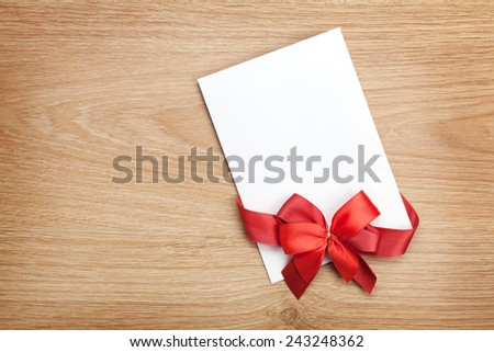 Blank valentines greeting card and red ribbon on wooden background with copy space