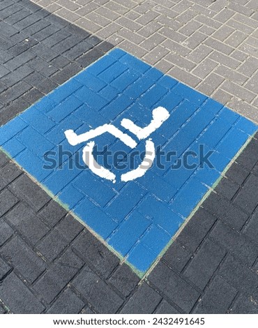 International wheelchair symbol. Disability sign painted on a brick sidewalk.
