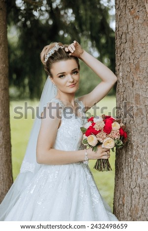 Portrait. A brunette bride in a dress and a veil, with a chic crown, poses with a bouquet near a tree. Silver jewelry. Beautiful makeup and hair. Autumn wedding. celebration