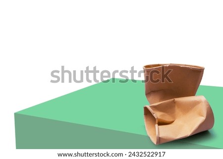 Crumpled used brown paper cup setting on green mockup isolated on white background. Environmental friendly concepts. 