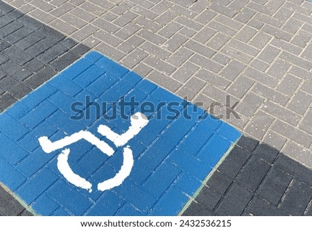 International accessibility sign painted on a brick sidewalk. Wheelchair sign on a floor. Disability sign at a bus stop 
