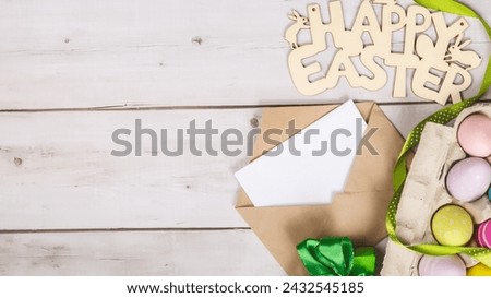 Art Happy Easter concept. Easter eggs, letter, greeting card and on white wooden background. Flat lay, top view, copy space.