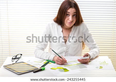 Young tired woman economist working with paper graphics, digital tablet and smart phone