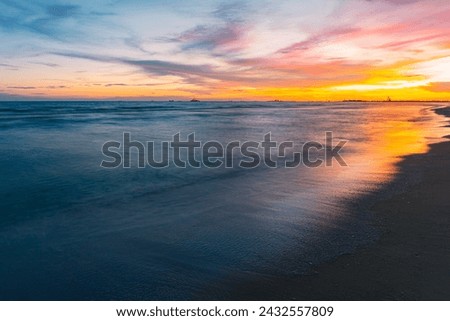 The sun setting on the left side of the picture. Glittering golden orange Contrasted with the blue sky There were many ships anchored further away—quiet evening sea atmosphere for a relaxing holiday.