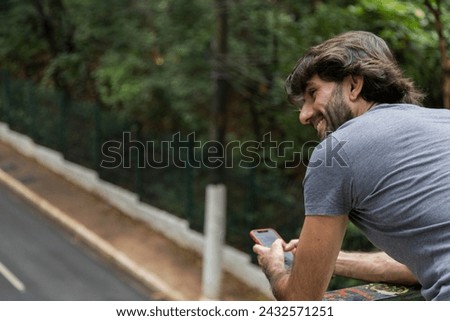 View of a young man with smartphone at daytime in a green park in the city. 
High quality video.