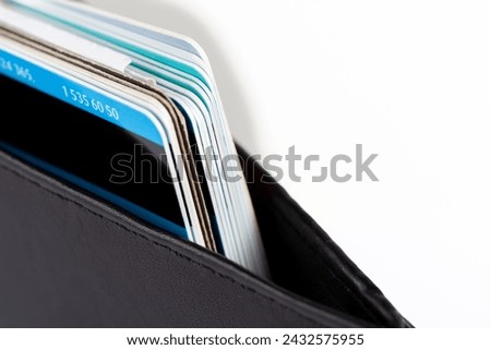 Macro detail closeup shot of several credit cards and multi-use cards neatly stacked inside a classic elegant black wallet. Personal private business and finance management, payment methods concept