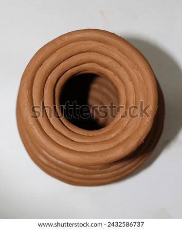 A clay pot is a container made of clay, used for cooking, storing food, or planting. It distributes heat evenly for slow cooking, and its porous nature circulates air and moisture, keeping food fresh. Royalty-Free Stock Photo #2432586737