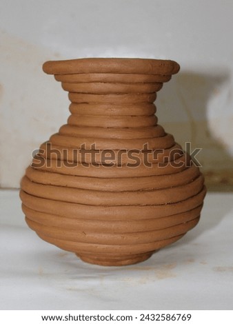 A clay pot is a container made of clay, used for cooking, storing food, or planting. It distributes heat evenly for slow cooking, and its porous nature circulates air and moisture, keeping food fresh. Royalty-Free Stock Photo #2432586769