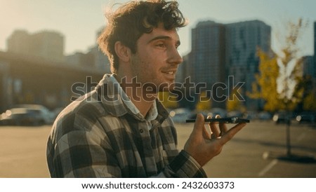 Caucasian man walking outside recording voicemail speakerphone handsome guy use virtual assistant app smartphone record audio message in city smiling male chatting with friends mobile phone messenger Royalty-Free Stock Photo #2432603373