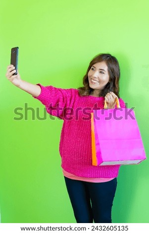 photograph pregnant woman fat belly, taking a selfie with shopping bags smiling happily. green background
