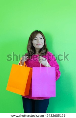 photograph of a satisfied and confident woman with her shopping bags on a green background.