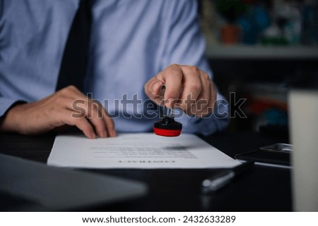 Man stamping approval of work finance banking or investment marketing documents on desk.	