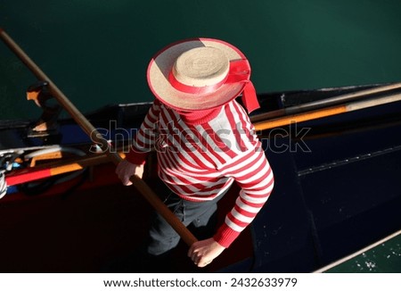 Venetian gondolier with the red and white striped shirt while rowing the Gondola in the Grand Canal in Venice Royalty-Free Stock Photo #2432633979