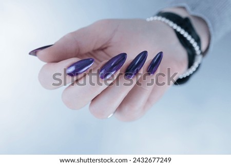 Female hands with long nails and dark purple manicure 