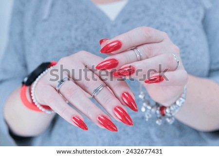 Female hand with long nails and a bottle of bright red nail polish