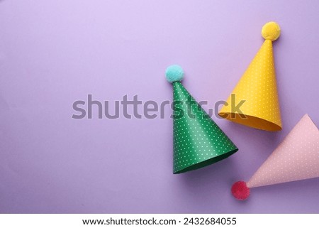 Beautiful party hats on purple background, top view. Space for text