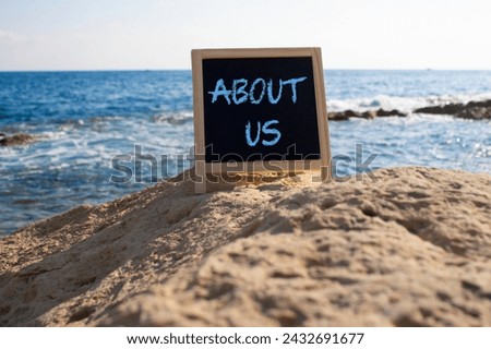About us symbol. Concept word About us on black chalk background. Beautiful sea background. Business and About us concept. Copy space