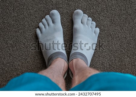 A close up of a man wearing toe socks. Royalty-Free Stock Photo #2432707495