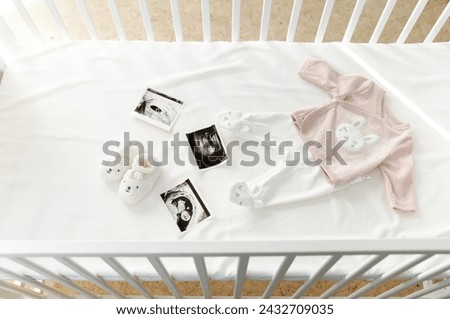 ultrasound picture and clothes in a crib. preparing for the arrival of the baby. baby clothes. childbirth details