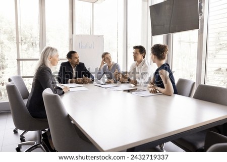 Five diverse office employee listen to male teammate, boss or leader make speech, share ideas, business vision, solutions, sales results at formal meeting briefing with workmates in modern board room Royalty-Free Stock Photo #2432719337