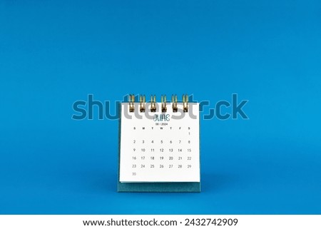 June 2024 mini desk calendar on blue color background. Royalty-Free Stock Photo #2432742909