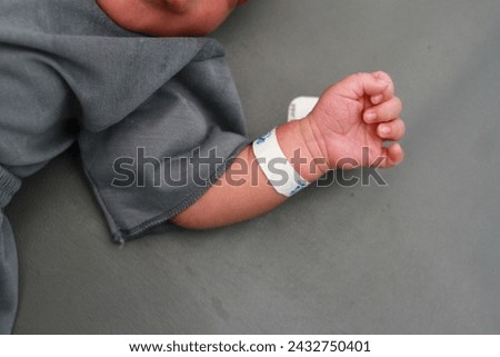 Newborn baby in hospital with identification bracelet tag name.