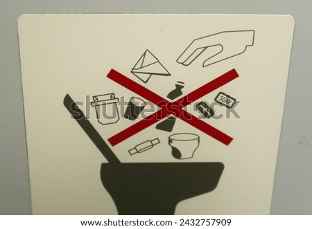 Airplane bathroom sign and fixture. Sign for no trash in toilet. Do not flush  garbage. Use the trash can.
