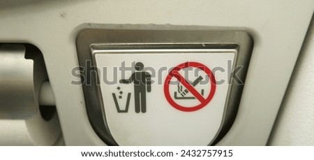 Airplane bathroom sign and fixture. No smoking in the bathroom. Put trash in the trash can. No cigarettes in the trash.