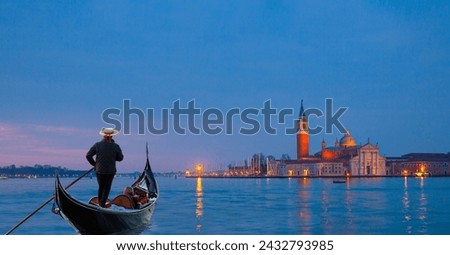 Venetian gondolier punting gondola through grand canal waters - View of San Giorgio Island in Venice with wooden buoys in Giudecca Canal  Royalty-Free Stock Photo #2432793985