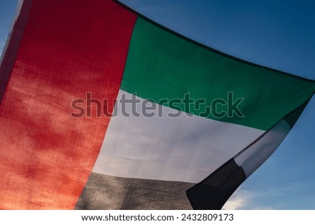 National Flag Of UAE Waving In The Wind sunset. Flag of United Arab Emirates on Sun Background. Sign of Dubai. National Independence Day or Flag