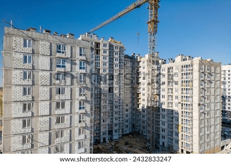 A crane stands atop a tall building, showcasing ongoing construction work in an urban setting. Royalty-Free Stock Photo #2432833247