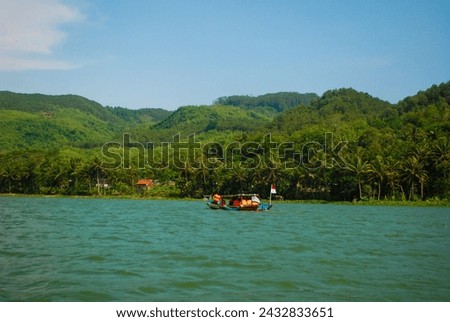 Boats across the river carry tourists across the serayu river, wearing orange life jackets