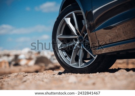 Close-up view of wheel of sports car at the gravel road Royalty-Free Stock Photo #2432841467
