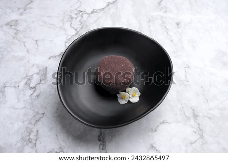 Traditional japanese mochi dessert with currant. Mochi ice cream on a black plate, marble background with copy space