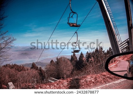 The chair lift in the blue sky. Suggestive view from Mottarone mountain (Stresa side) on a winter morning.  Lakes and mountains in the background. Piedmont - Italy. Royalty-Free Stock Photo #2432878877