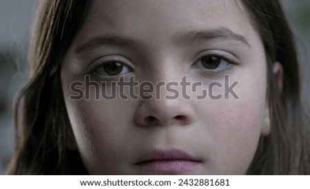 Macro tight close-up of child's face looking at camera with solemn blank expression. Little girl portrait Royalty-Free Stock Photo #2432881681