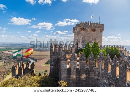 Tower of homage, walls and battlements with the flags of Spain and Andalusia in the castle of Almodovar del Rio. Royalty-Free Stock Photo #2432897485