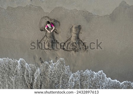 Child play with sand on beach above top drone view