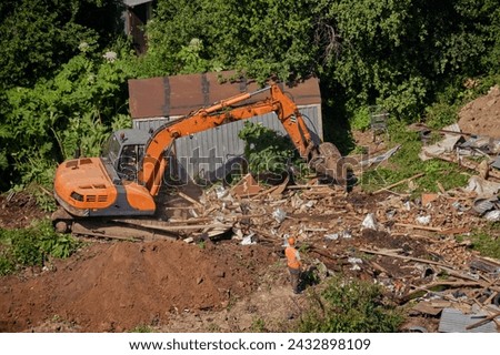 Bulldozer and construction machinery destroys illegal buildings in the park. Destroy of an illegally built old building in nature Royalty-Free Stock Photo #2432898109