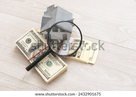 dollar money, toy house and magnifying glass