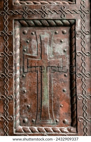 Detail form an ancient church door with cross sign relief on copper