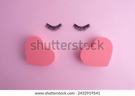 False eyelashes, makeup sponge in the shape of a heart for eye makeup on a colored background. Concept of eyelash extension tool, cosmetic procedures, appearance enhancement. Copy space