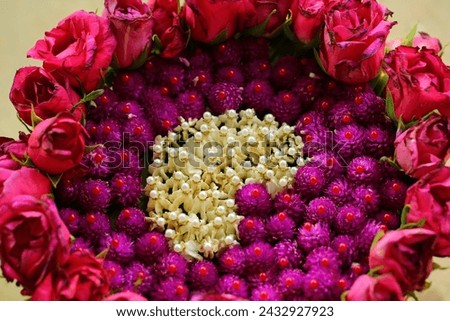 Arrange and decorate flowers on a tray to serve as a background for a heart picture.