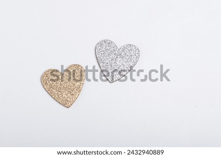 A silver and a golden heart on a white background