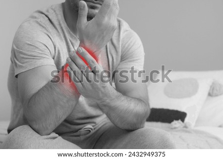 Man suffering from rheumatism at home, closeup. Black and white effect with red accent in painful area