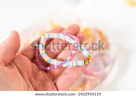 Little girl's charming bracelets adorned with clay and sea beads. Royalty-Free Stock Photo #2432954119