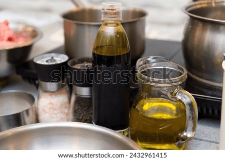 A culinary setup with olive oil in a clear glass jug, vinegar in a bottle, and salt and pepper grinders, ready for food seasoning.
